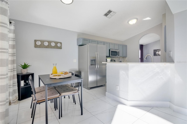 kitchen featuring sink, appliances with stainless steel finishes, gray cabinetry, decorative backsplash, and kitchen peninsula