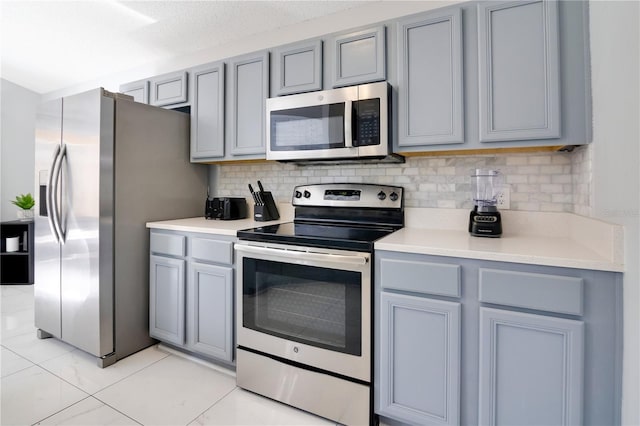 kitchen featuring tasteful backsplash, gray cabinets, and appliances with stainless steel finishes