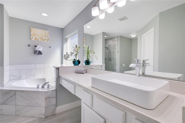 bathroom featuring hardwood / wood-style flooring, vanity, and separate shower and tub