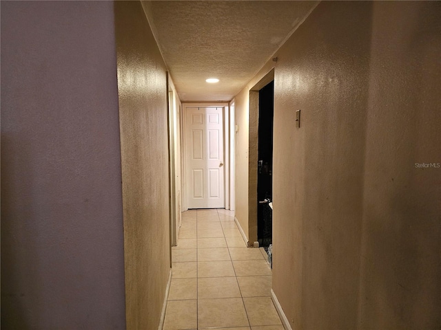 hallway with light tile patterned floors and a textured ceiling