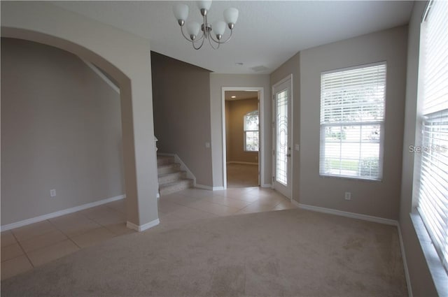 carpeted foyer entrance with a notable chandelier