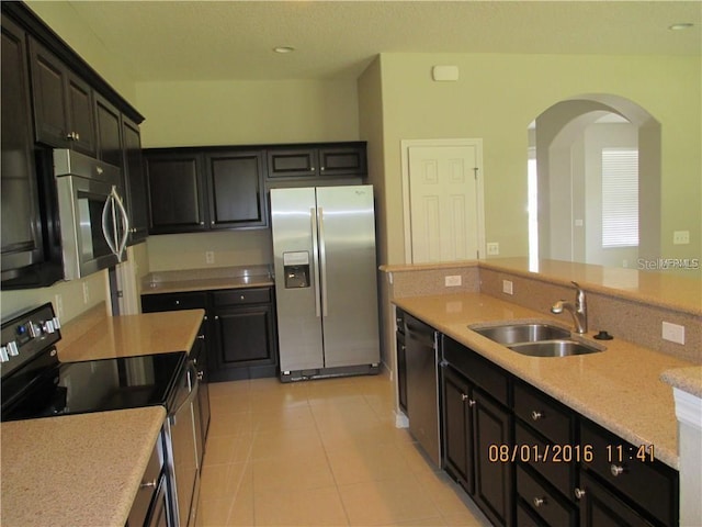 kitchen featuring stainless steel appliances, light stone countertops, sink, and light tile patterned floors