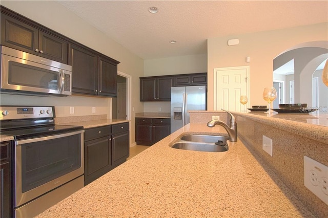 kitchen featuring stainless steel appliances, light stone countertops, and sink