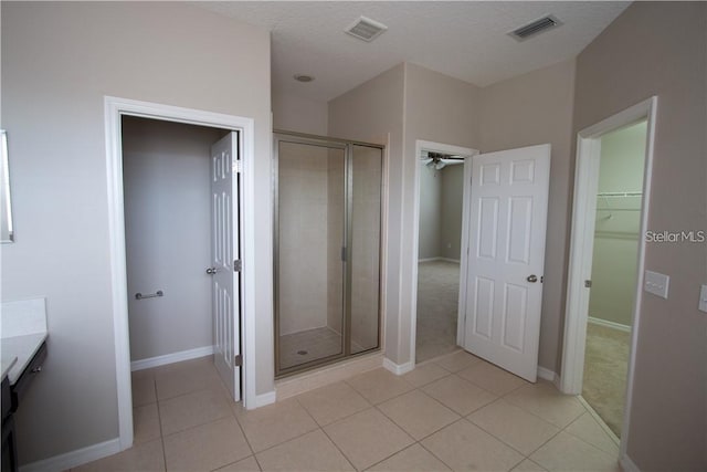 bathroom with a shower with door, vanity, tile patterned floors, and a textured ceiling