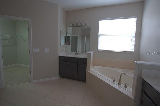 bathroom featuring vanity, a relaxing tiled tub, and tile patterned floors