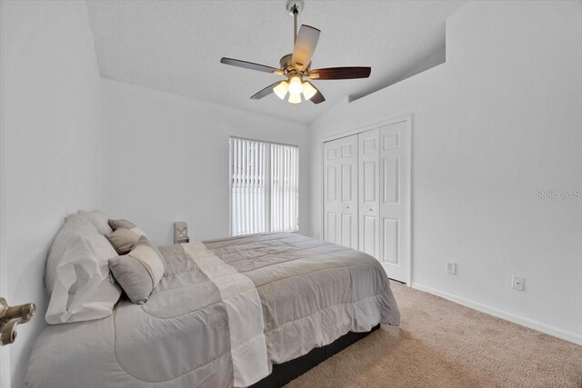 bedroom with ceiling fan, lofted ceiling, carpet flooring, and a closet