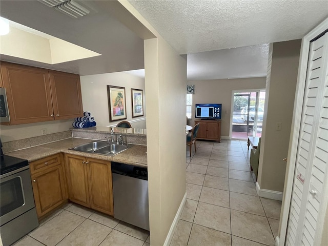 kitchen featuring stainless steel appliances, sink, light tile patterned floors, and a textured ceiling