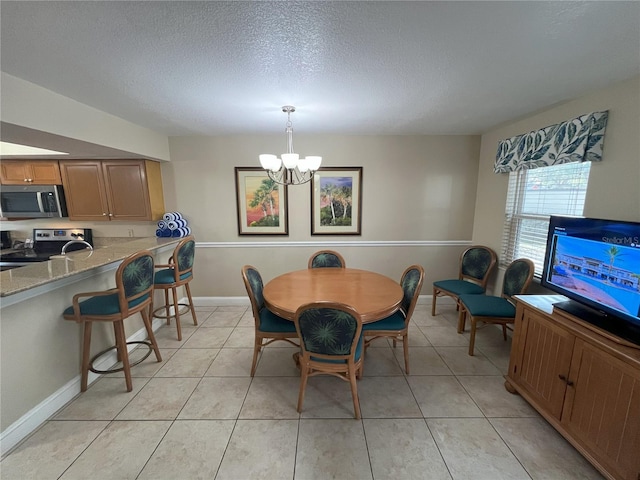 dining space with an inviting chandelier, light tile patterned flooring, and a textured ceiling