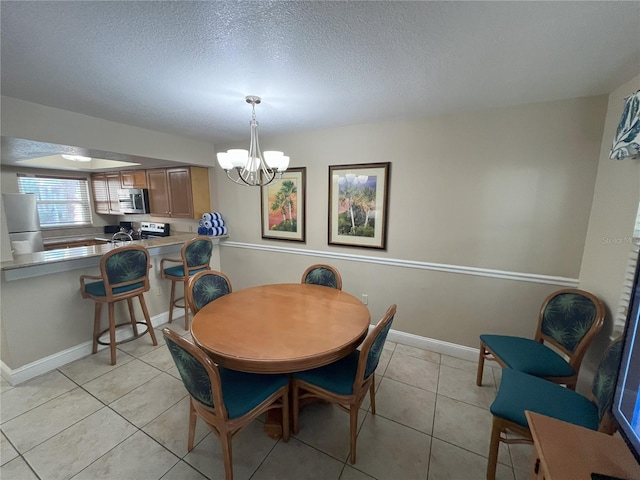 dining area with light tile patterned floors, a textured ceiling, and a chandelier