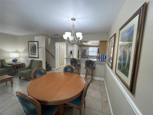 dining space featuring a chandelier, a textured ceiling, and light tile patterned floors