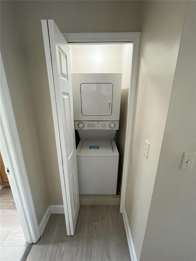 laundry area featuring stacked washer and dryer and light hardwood / wood-style floors