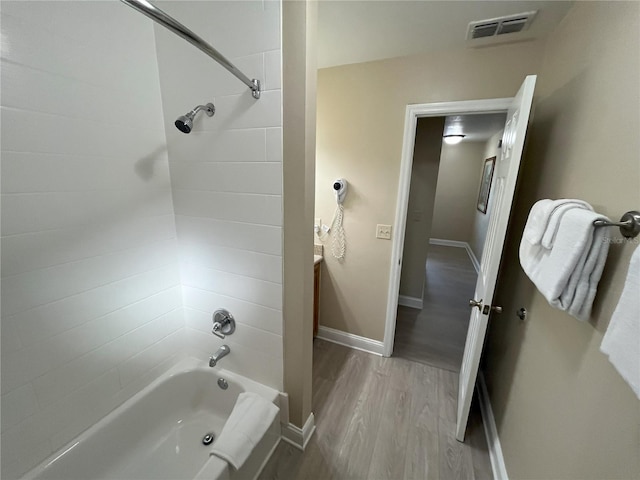 bathroom with tiled shower / bath, vanity, and wood-type flooring