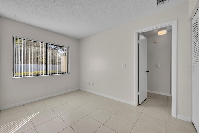 spare room with a textured ceiling and light tile patterned floors