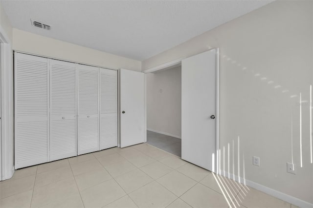 unfurnished bedroom featuring a closet, a textured ceiling, and light tile patterned floors