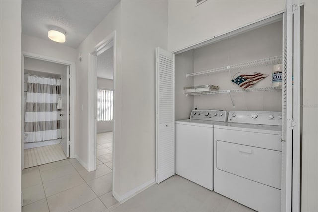 laundry area with light tile patterned flooring, separate washer and dryer, and a textured ceiling