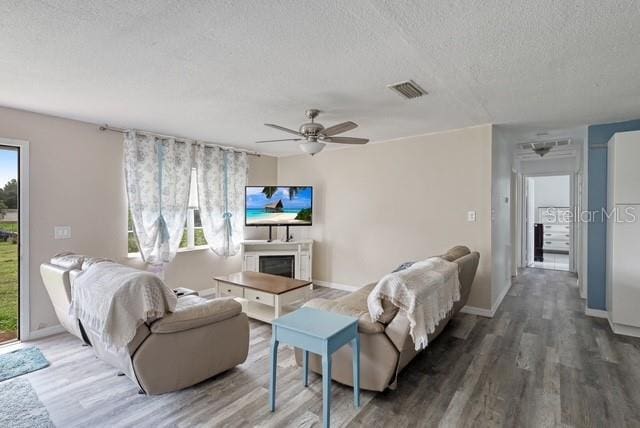 living room with ceiling fan, a textured ceiling, and dark hardwood / wood-style flooring