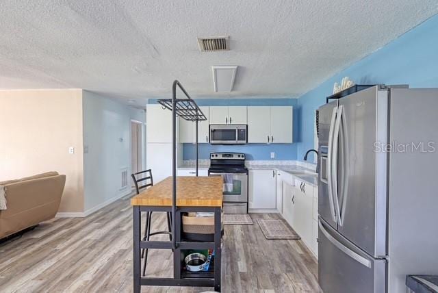 kitchen featuring stainless steel appliances, sink, light wood-type flooring, and white cabinets