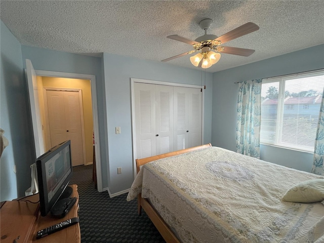 bedroom featuring ceiling fan, a closet, a textured ceiling, and dark colored carpet