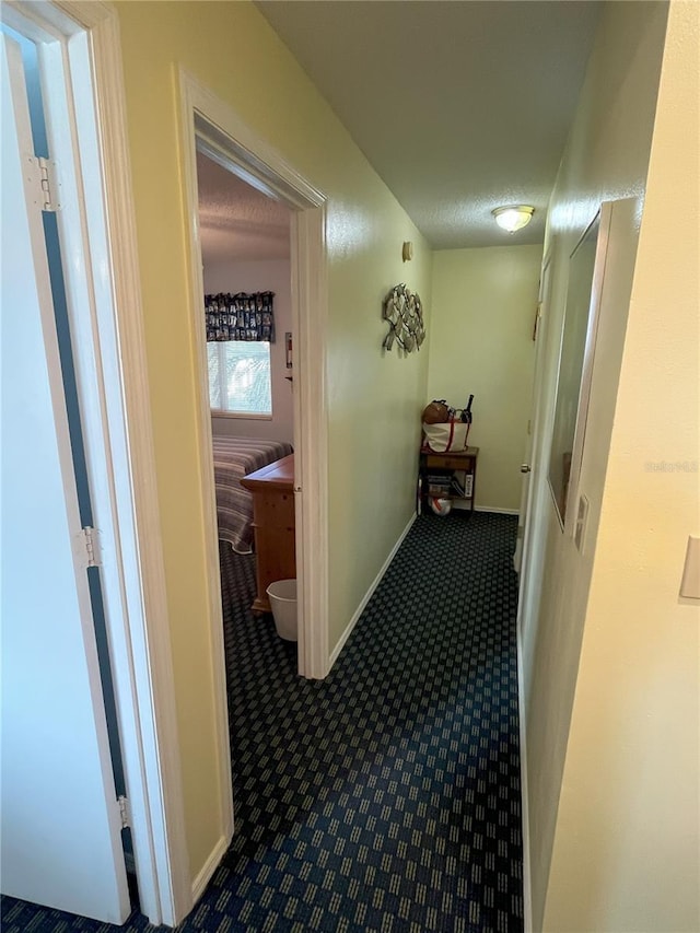 hallway with a textured ceiling and carpet