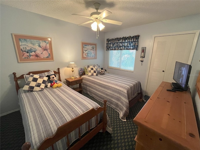 bedroom featuring ceiling fan, dark carpet, and a textured ceiling