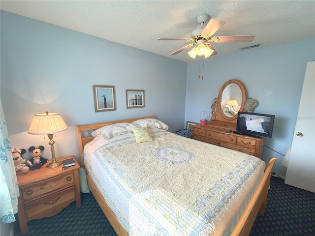 bedroom with visible vents, dark carpet, and a textured ceiling