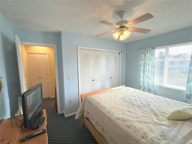 bedroom featuring a textured ceiling, ceiling fan, baseboards, a closet, and dark colored carpet