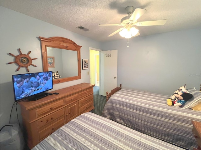 carpeted bedroom featuring a ceiling fan, visible vents, and a textured ceiling