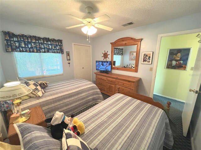 bedroom with a textured ceiling, carpet floors, visible vents, and a ceiling fan