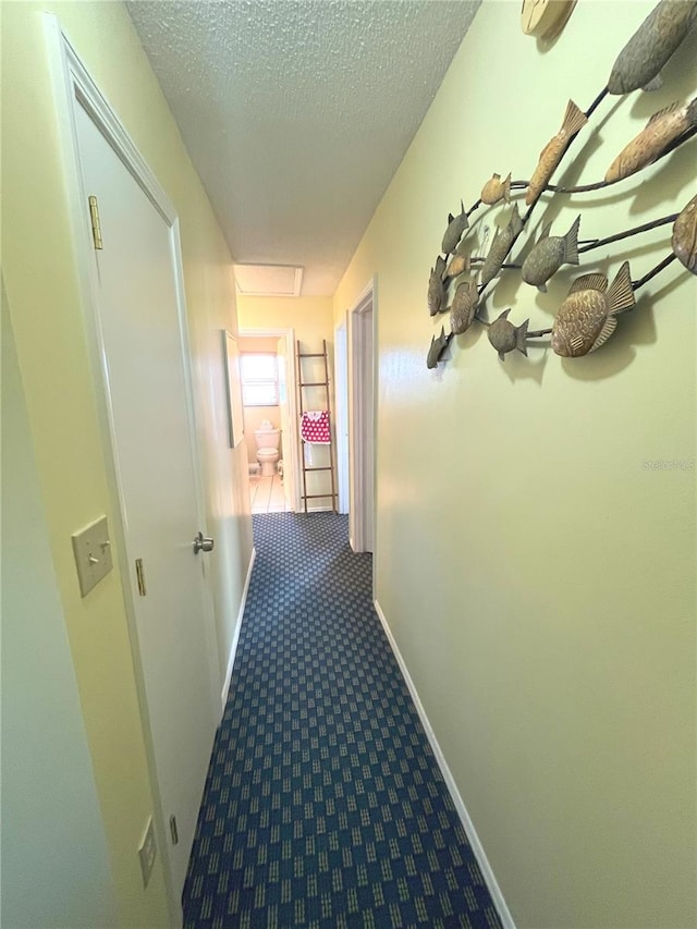 corridor featuring carpet floors, a textured ceiling, and baseboards