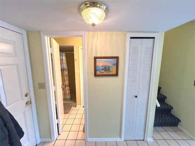 corridor featuring light tile patterned floors, stairway, and baseboards