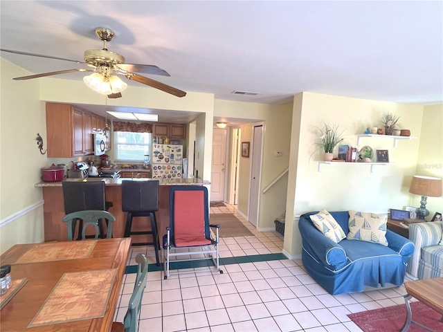 living room featuring baseboards, visible vents, a ceiling fan, and light tile patterned flooring