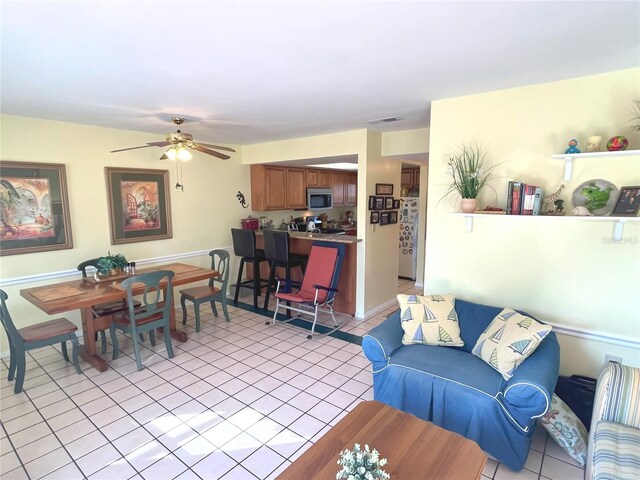 living area with light tile patterned flooring, ceiling fan, and visible vents