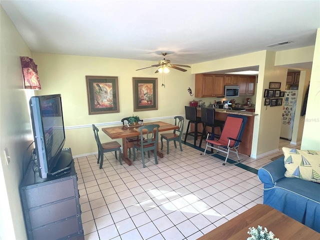 dining area with light tile patterned floors, baseboards, visible vents, and a ceiling fan
