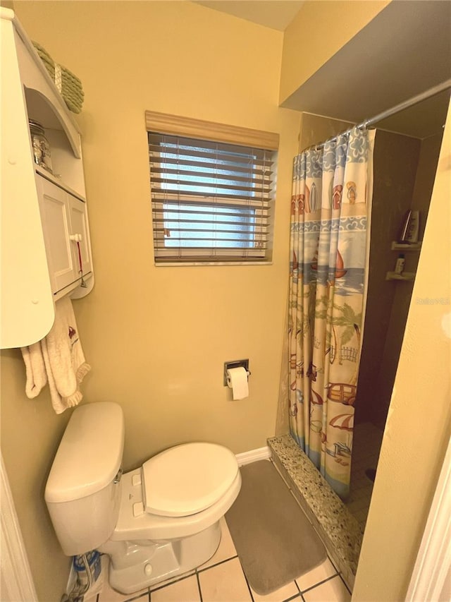 bathroom featuring toilet, a shower stall, baseboards, and tile patterned floors
