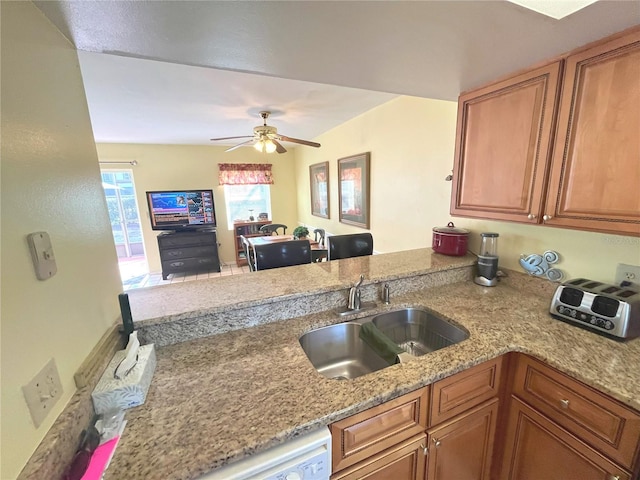 kitchen featuring a peninsula, brown cabinetry, a sink, and open floor plan