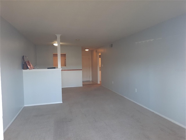 unfurnished living room with decorative columns and carpet floors