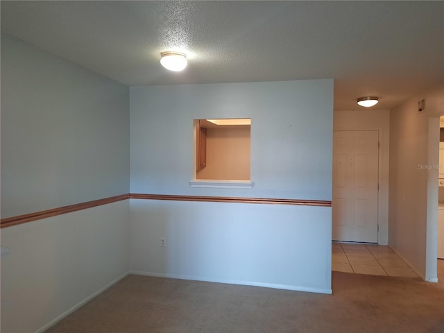 spare room with light colored carpet and a textured ceiling