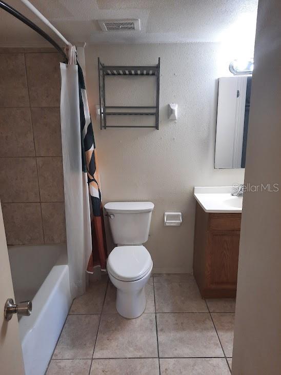 full bathroom with tile patterned floors, toilet, shower / bath combo with shower curtain, and vanity