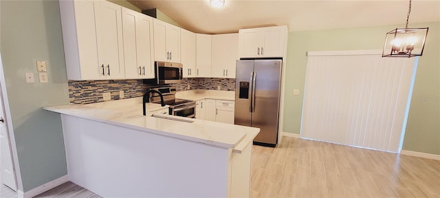 kitchen with appliances with stainless steel finishes, pendant lighting, white cabinets, kitchen peninsula, and light hardwood / wood-style flooring