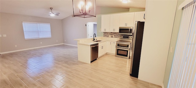 kitchen with vaulted ceiling, sink, white cabinets, kitchen peninsula, and stainless steel appliances