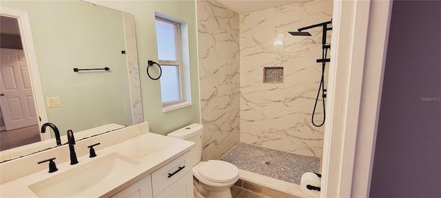 bathroom with vanity, tiled shower, and toilet