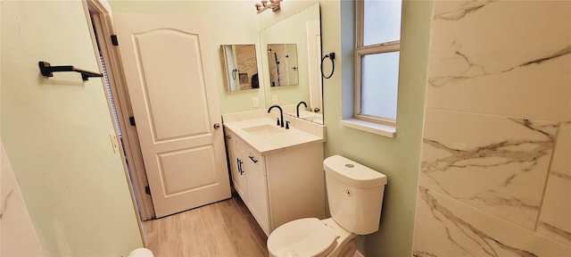 bathroom featuring vanity, wood-type flooring, a healthy amount of sunlight, and toilet