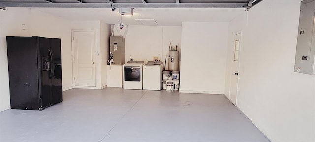 garage featuring heating unit, washer and clothes dryer, water heater, and black fridge