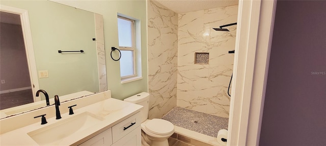 bathroom featuring vanity, a tile shower, and toilet