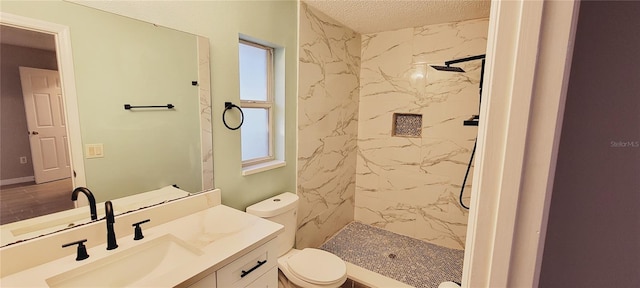 bathroom with vanity, a tile shower, a textured ceiling, and toilet