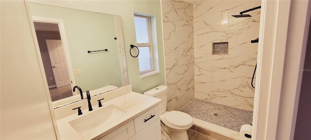 bathroom with vanity, tiled shower, and toilet