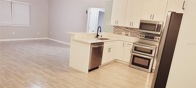 kitchen featuring sink, stainless steel appliances, white cabinets, decorative backsplash, and kitchen peninsula