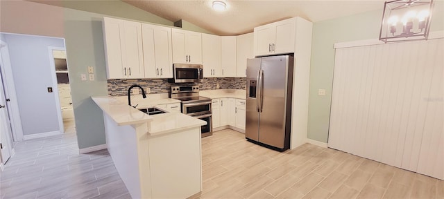 kitchen with sink, white cabinetry, hanging light fixtures, stainless steel appliances, and kitchen peninsula