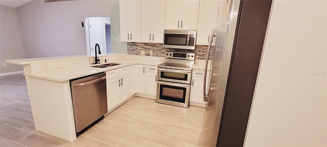 kitchen featuring sink, appliances with stainless steel finishes, white cabinets, decorative backsplash, and kitchen peninsula