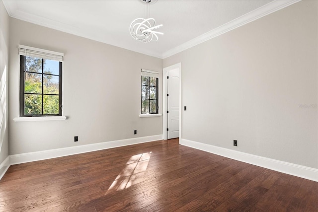 empty room with crown molding, a healthy amount of sunlight, dark hardwood / wood-style floors, and a chandelier